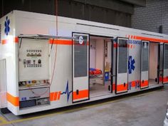 an orange and white train car is parked in a garage with its doors open to let people inside