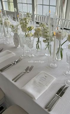 the table is set with white flowers and silverware for an elegant wedding reception or special event