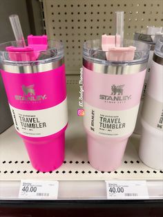 two travel tumblers are sitting on the shelf in a store, one is pink and the other is white