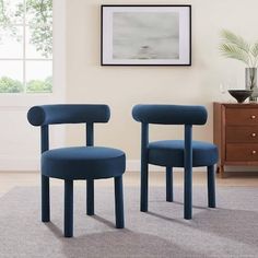 two blue chairs sitting on top of a carpeted floor in front of a window