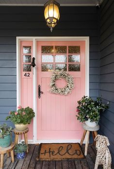 a pink front door with two potted plants