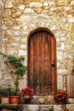 an old stone building with potted plants and a wooden door