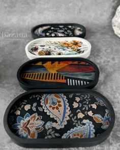 three oval trays with designs on them sitting on the ground next to each other