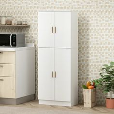 a microwave oven sitting on top of a white cabinet next to a potted plant