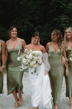 a group of women standing next to each other wearing dresses and holding bouquets in their hands