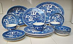 a blue and white porcelain dinner set on the floor in front of a tile wall