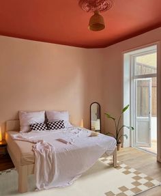 a bedroom with pink walls and checkered rugs on the floor next to a bed