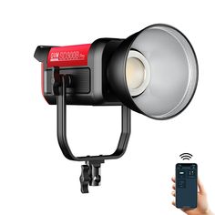 a person holding a cell phone in front of a camera and light on a tripod