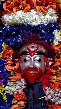 a mask with flowers around it and a man's face painted in red, white, and blue