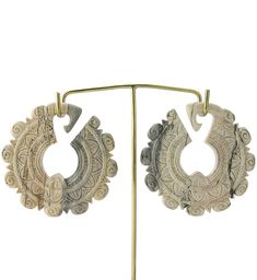 two pairs of earrings are hanging from a metal stand on a white background, with one earring in the shape of a circle