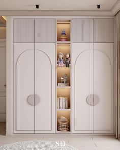 an empty room with two white cupboards and bookshelves on the wall, next to a round table