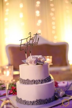 a wedding cake sitting on top of a table next to a wine glass and candle