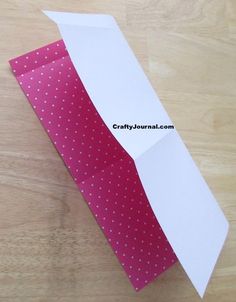 an open white paper bag sitting on top of a wooden table next to a pink polka dot tie