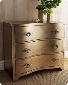 a wooden dresser with flowers in a vase on it's top and bottom drawer