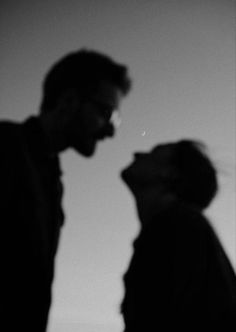 a man and woman standing next to each other in front of a sky with the moon behind them