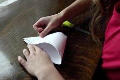 a person cutting paper on top of a wooden table