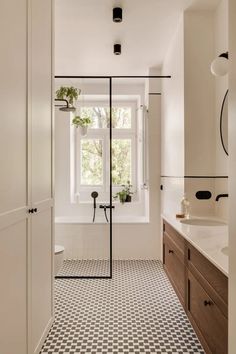 a bathroom with a black and white checkerboard floor, sink, shower stall and window