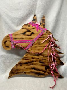 a wooden horse head with pink ribbon on it