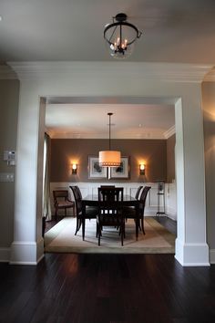 a dining room table and chairs in front of an open doorway with lights on the wall