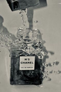 black and white photograph of chanel perfume bottle being filled with water from faucet