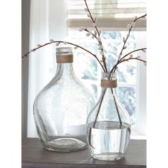 two glass vases sitting on top of a table next to each other with flowers in them