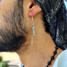 Mens Edgy & Boho Earring Collection, Personalized Minimalist Designs with Chain Long, Feather, Fringe, Tassel, and Leather Accents - Pirate, Cowgirl & Boho Jewelry Styles - Perfect for the Modern Dangle Earring Enthusiast. Dive into the world of bohemian style with this meticulously designed Men's Leather fringe tassel earring. Delicately adorned with a silver-plated chain and a feather at the end, it radiates a touch of edgy charm and boho flair - a perfect blend of bohemian tassel earrings and Casual Single Dangle Earring, Mens Dangle Earrings, Minimalist Earring, Edgy Accessories, Earring Stand, Boho Style Jewelry, Leather Fringe, Mens Leather, Tassel Fringe