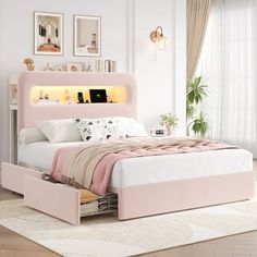 a pink bed with drawers underneath it in a white and light colored room, along with pictures on the wall