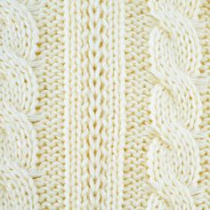 the texture of a knitted blanket is shown in white and beige colors, as seen from above