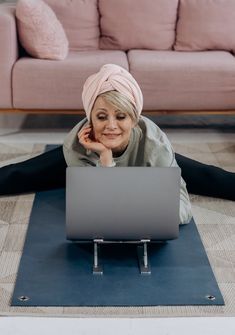 a woman laying on the floor with her laptop in front of her, smiling at the camera