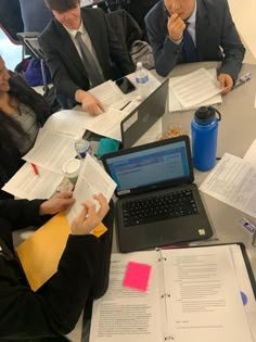 people sitting around a table with papers and laptops