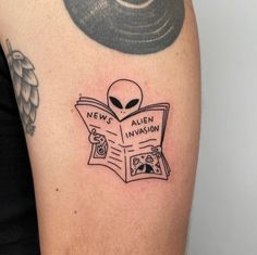 an alien reading a news paper tattoo on the arm