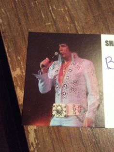 an elvis presley concert ticket sitting on top of a wooden table next to a microphone