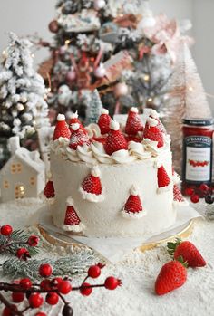 a white cake with strawberries on top and christmas trees in the backgroud