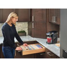 a woman standing in front of a kitchen counter with an open drawer