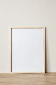 an empty wooden frame sitting on top of a wooden table next to a white wall