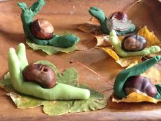 some figurines made to look like snails and leaves on a wooden platter