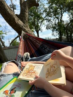 a person sitting in a hammock reading a book and holding an open book