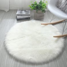 a white round rug sitting on top of a wooden floor next to a chair and potted plant