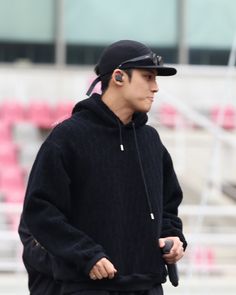 a man in black jacket and hat with ear buds on his ears walking down the street