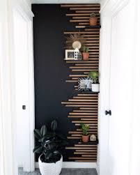 a black wall with wooden slats on the side and potted plants next to it