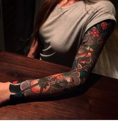 a woman sitting at a wooden table with a tattoo on her arm and leg behind her