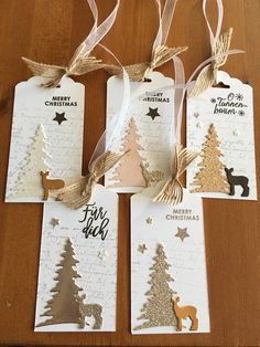 four tags with christmas trees and deers hanging from them on a wooden table top