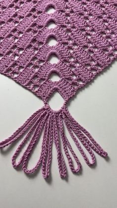 a pink crocheted shawl with tassels