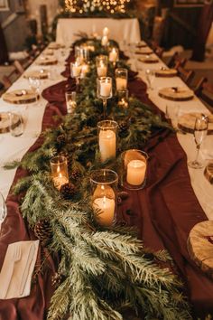 a long table with candles and evergreen garland