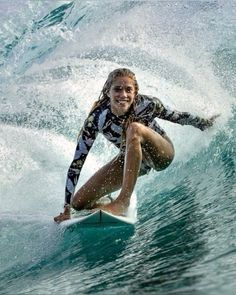 a woman riding a wave on top of a surfboard