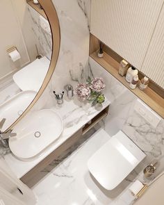 a bathroom with marble counter top and white toilet next to a round mirror above the sink