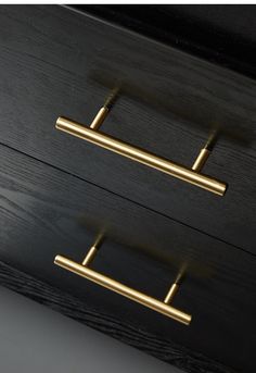 two brass handles on a black drawer