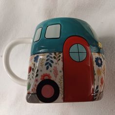 a blue and red coffee mug with flowers on it's side, sitting on a white surface