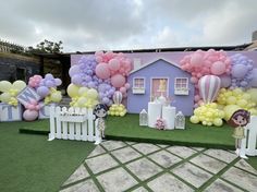 an outdoor party with balloons and decorations on the lawn, in front of a house