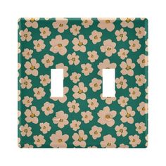 a green and white flowered light switch cover with two toggles on each side